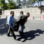 Afghan men carry an injured man after a blast in Kabul, Afghanistan