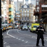 A police officer strecthes cordon tape accross the road near Borough Market after an attack left 6 people dead and dozens injured in London
