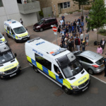 Police vans leave carrying a number of women who were detained after a block of flats was raided in Barking, east London