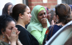 People react near a tower block severely damaged by a serious fire, in north Kensington, West London