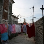 A woman hangs up laundry to dry on a rooftop of a building, in Havana